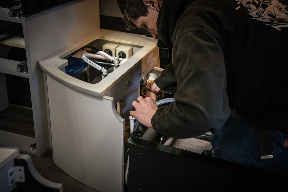 Raccordements d’eau et d’électricité sous le meuble d’un van