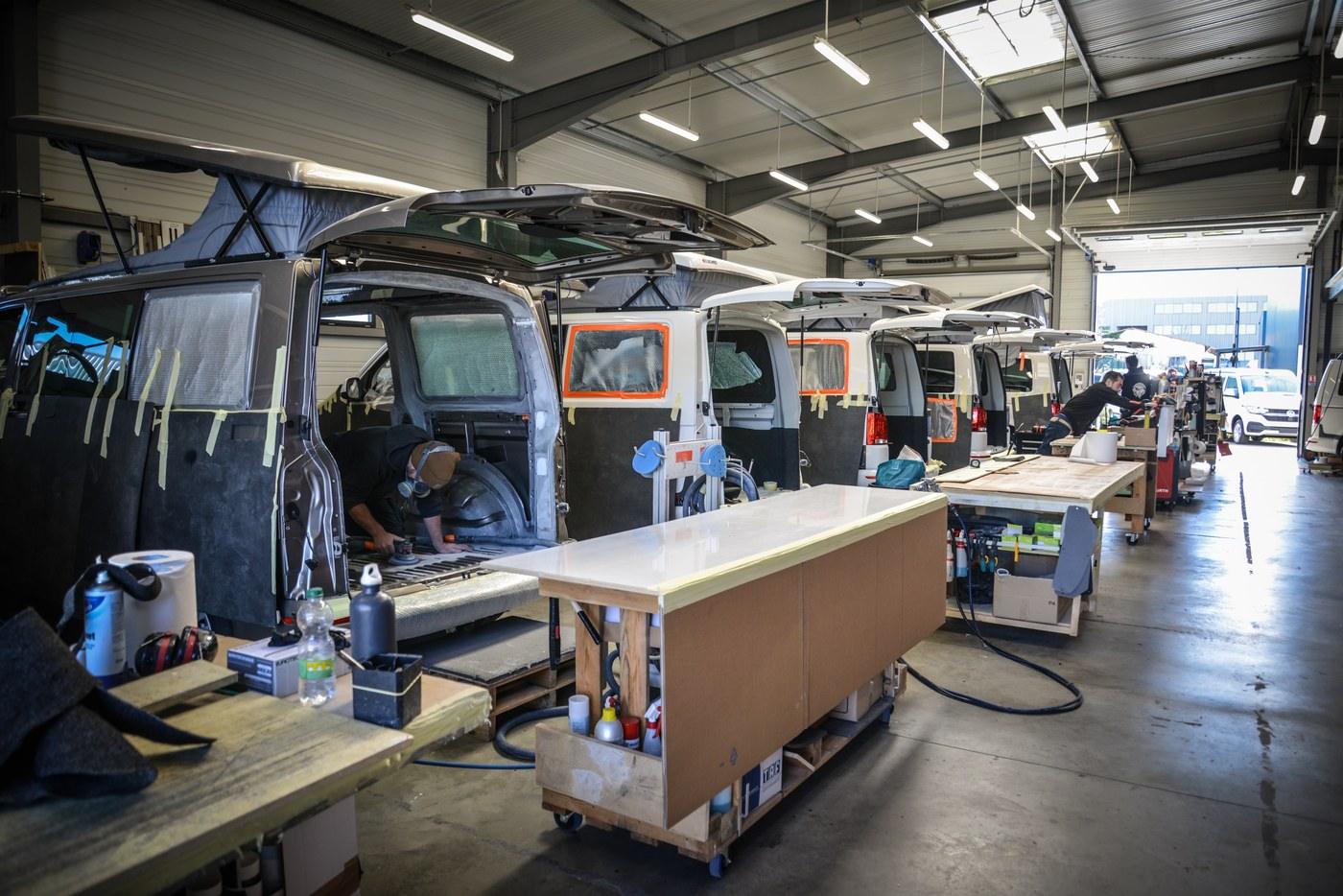Vue d’ensemble de l’atelier Eco Campers, plusieurs vans en cours d’aménagement